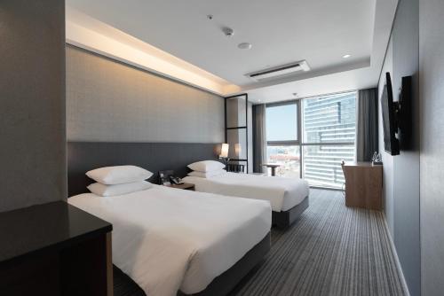 a hotel room with two beds and a window at Northharbor Hotel in Busan