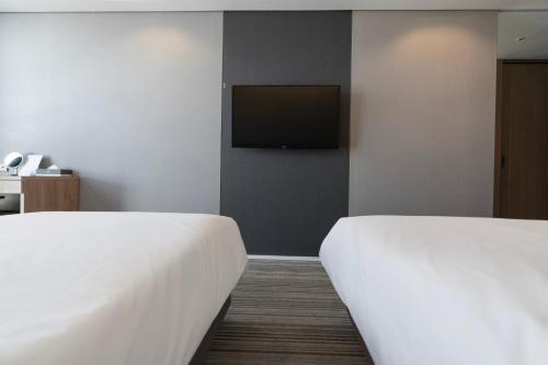 a hotel room with two beds and a flat screen tv at Northharbor Hotel in Busan