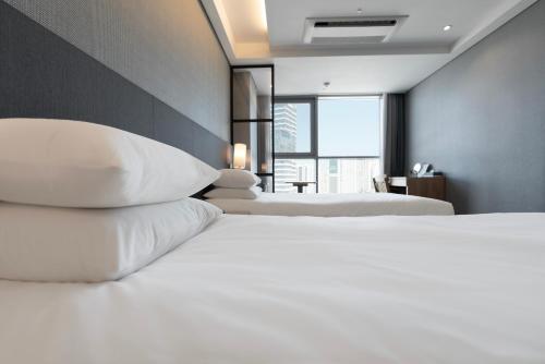 a hotel room with two beds with white pillows at Northharbor Hotel in Busan
