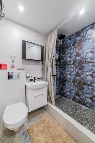 a bathroom with a toilet and a stone wall at Malena Apartments in Šiauliai