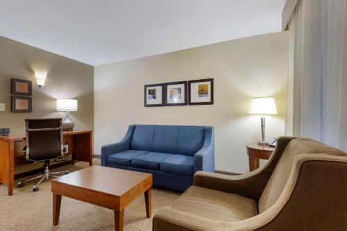 a living room with a blue couch and a desk at Comfort Suites Near Potomac Mills in Woodbridge
