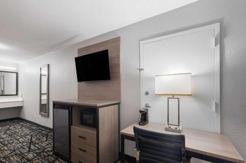 a hotel room with a desk and a television at Baymont by Wyndham Mobile/Tillmans Corner in Tillmans Corner