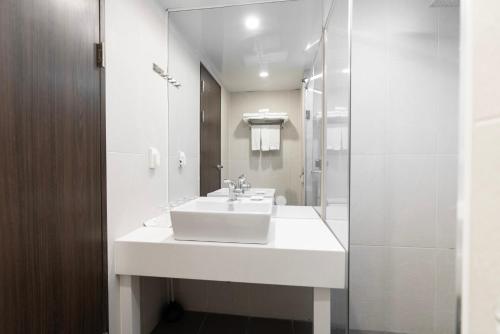 a white bathroom with a sink and a shower at Northharbor Hotel in Busan