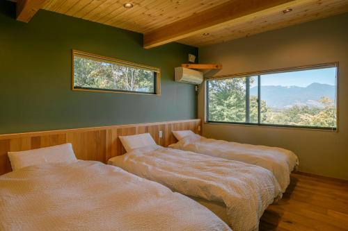 小諸市にある女性のための森サウナ 一棟貸し宿 SORA 宙 Forest sauna villa SORAの大きな窓付きの客室で、ベッド2台が備わります。