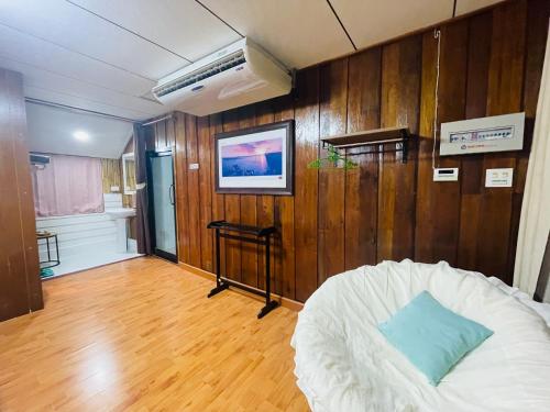a living room with a white couch and wooden walls at บ้านริมเลปากประ Banrimlay Pakpra in Phatthalung
