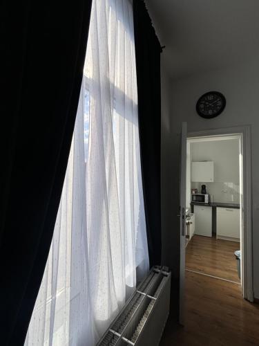 a window with a white curtain in a room at Studio Issa in Brussels