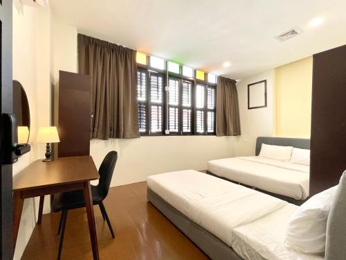 a hotel room with two beds and a desk and a chair at INN Lebuh Melayu in George Town