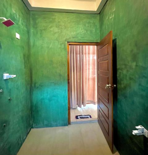 a green room with a door and a window at Maccan's Village in Arugam Bay