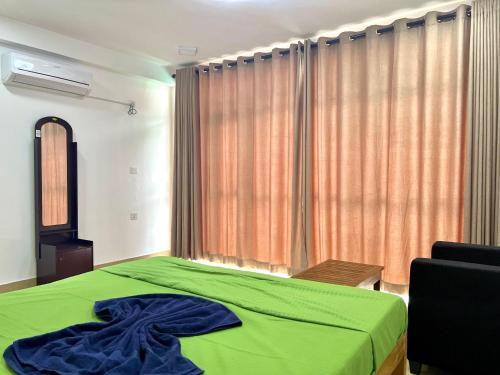 a bedroom with a green bed and a window at Maccan's Village in Arugam Bay