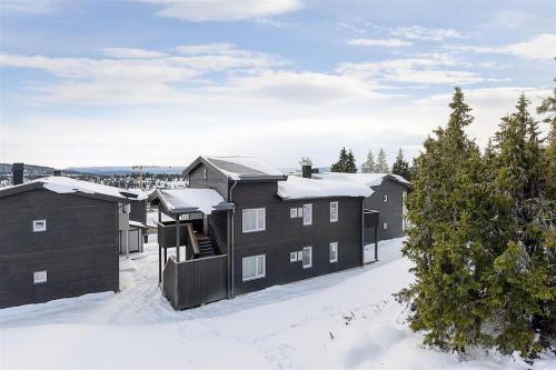 un bâtiment sous la neige avec des arbres couverts de neige dans l'établissement Leilighet sentralt på Sjusjøen, 11 sengeplasser, à Ringsaker
