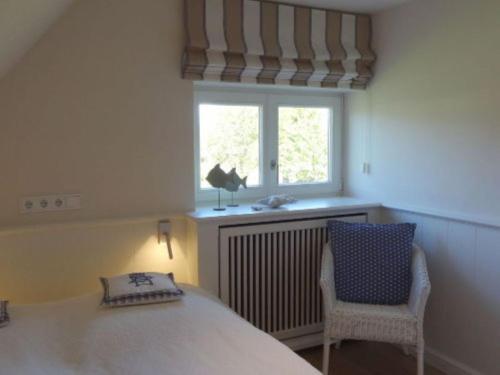 a bedroom with a bed and a window and a chair at Sylthus-Haithabu in Wenningstedt