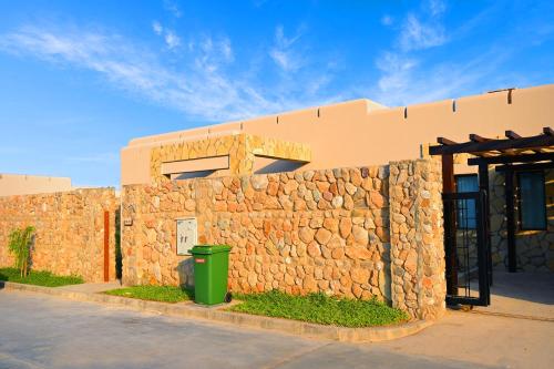 a stone wall next to a building with a trash can at Wateera Jebel Sifah in As Sīfah