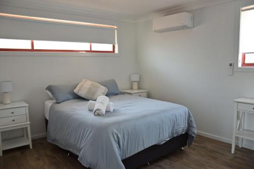 a bedroom with a bed with two white towels on it at High 5 in South West Rocks