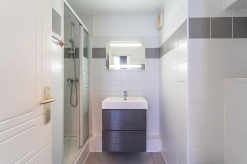 une salle de bain blanche avec un lavabo et une douche dans l'établissement Résidence Jardin des plantes PARIS, à Paris