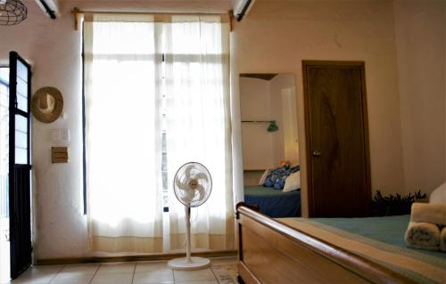 a bedroom with a bed and a window and a fan at Yellow flat-estudio Oaxaca Centro in Oaxaca City