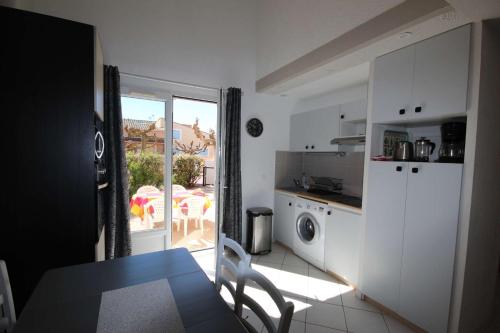 kuchnia ze stołem i drzwi na patio w obiekcie Villa plein sud, 4 couchages, en résidence LES ONDINES avec piscine commune, 500 m de la mer LROND28 w mieście Portiragnes