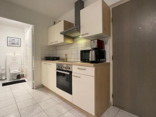 a kitchen with white cabinets and a microwave at T2 5 Lys - centre ville, parking privé in Saint-Louis