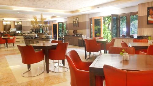 a restaurant with red chairs and tables in a room at Lorin Dwangsa Solo Hotel in Solo