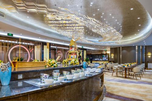 a restaurant with a bar with chandeliers and tables at Beijing Continental Grand Hotel in Beijing