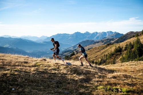 two people running on a hill in the mountains at Dorfresort Kitzbühel by ALPS RESORTS in Reith bei Kitzbühel