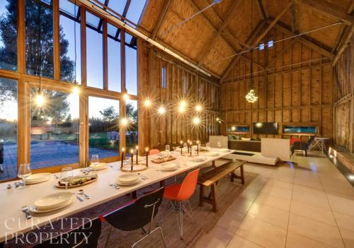 a dining room with a long table in a barn at Grand Suffolk Barn Conversion in Chelsworth