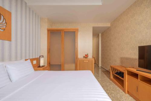 a bedroom with a white bed and a television at Trân Châu Beach & Resort in Ba Ria