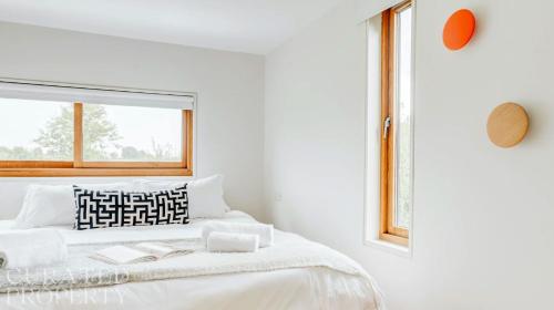 a white bedroom with a bed with a window at Grand Suffolk Barn Conversion in Chelsworth
