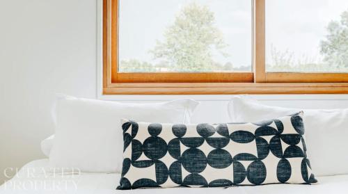a pillow sitting on a bed in front of a window at Grand Suffolk Barn Conversion in Chelsworth