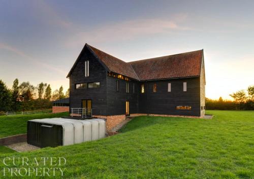 a black house with a water tank in the yard at Grand Suffolk Barn Conversion in Chelsworth