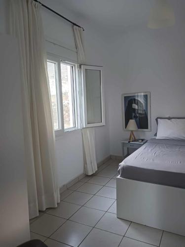 a white bedroom with a bed and a window at Ακροδεα in Áno Gávrion