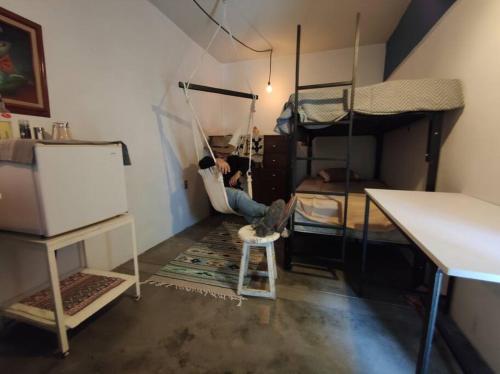 a man is sitting on a swing in a room with bunk beds at The azul flat room in Oaxaca City
