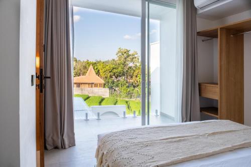 een slaapkamer met een bed en een groot glazen raam bij White Palm Villa in Canggu