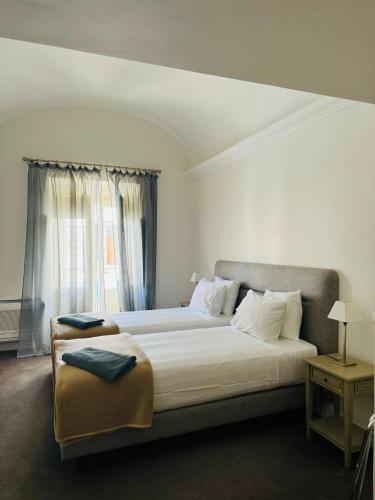 a bedroom with a large white bed with a window at SOLAR DOS FRADES in Ferreira do Alentejo