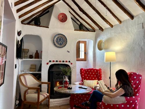a woman sitting in a living room reading a book at Las casillas de la Villa ALEGRÍAS in Montefrío