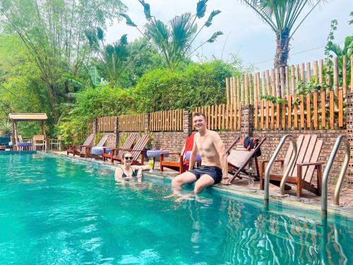 a man and a child sitting in a swimming pool at Tam Coc Central Bungalow-Hostel in Vũ Lâm