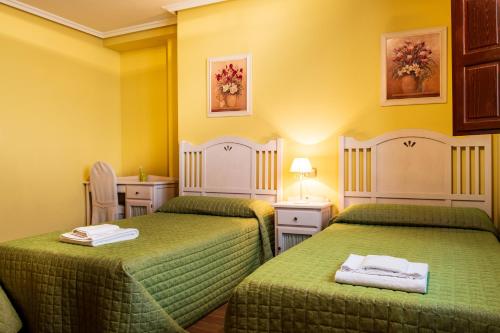 two beds in a room with yellow walls at Casa Rural Doña Manuela in Valdemierque