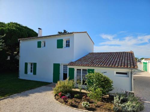 une maison blanche avec des volets verts et une cour dans l'établissement La Nout - Maison 8 personnes Bois-Plage-en-Ré, au Bois-Plage-en-Ré