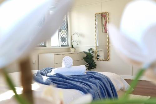 a bed with a blue blanket and a mirror at The Heavenly Haven in Brisbane