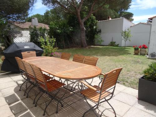 - une table en bois avec des chaises et un parasol dans la cour dans l'établissement La Nout - Maison 8 personnes Bois-Plage-en-Ré, au Bois-Plage-en-Ré