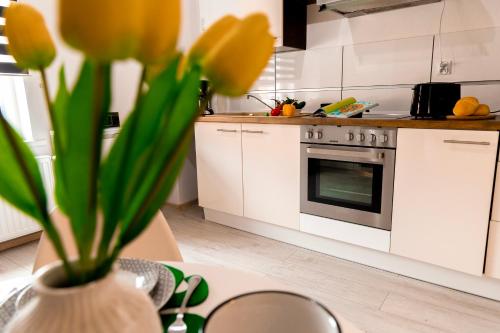 a kitchen with white cabinets and a vase with yellow flowers at Apartamenty Zieleniec-Julia 3 in Duszniki Zdrój