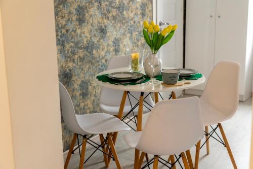 a dining room with white chairs and a table with yellow flowers at Apartamenty Zieleniec-Julia 3 in Duszniki Zdrój
