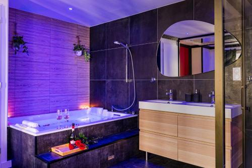 une salle de bain avec une baignoire, un lavabo et un miroir dans l'établissement Suite Jean Jaurès - Love Room, à Saint Etienne