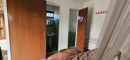 a bathroom with a door and a sink in a room at Hilltop Guest House in Ella