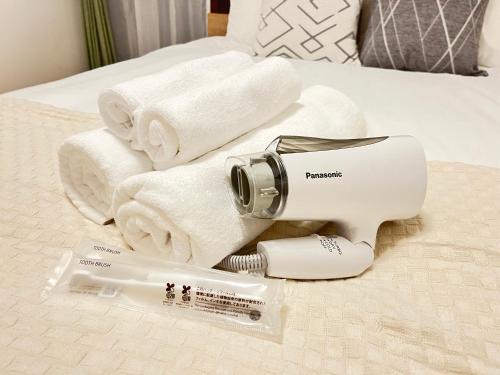 a white blow dryer sitting on a bed with towels at Casa Stella 18 by Liaison in Osaka
