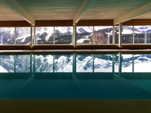 a building with a pool with snow covered mountains at Lovely Apartment in Tauplitz