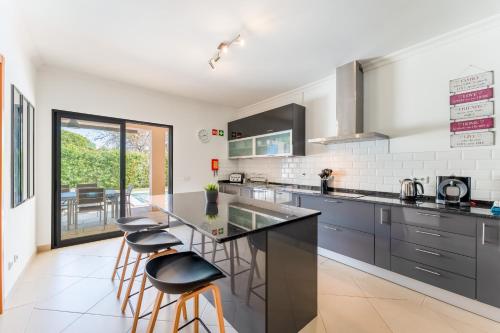 a kitchen with a counter and stools in it at Casa no Sol in Loulé