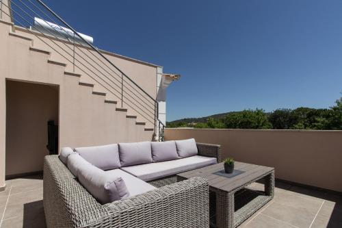 a wicker couch and a table on a balcony at Casa no Sol in Loulé