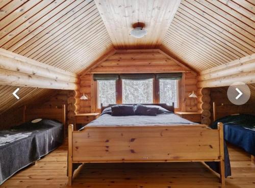 a bedroom with a bed in a log cabin at LIHAPULLIA Lac, sauna, plage privée, deux chalets rien que pour vous in Nieminen