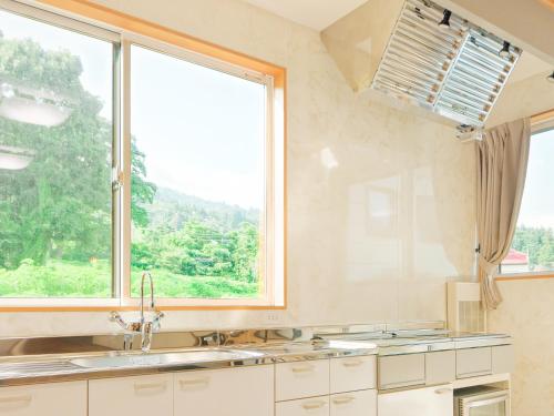 a kitchen with a sink and a large window at Togari Inn Suites in Iiyama