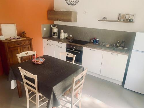 une cuisine avec une table et des chaises et une cuisine avec des placards blancs dans l'établissement Maison 2 chambres- grand jardin-WIFI - au cœur du village AUBETERRE -visites- conciergerie J&N, à Aubeterre-sur-Dronne